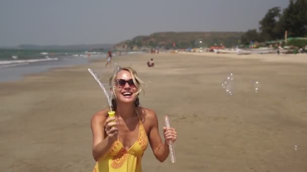 Mulher bonita na praia do mar sopra bolhas de sabão. Menina com bolhas de sabão . — Vídeo de Stock