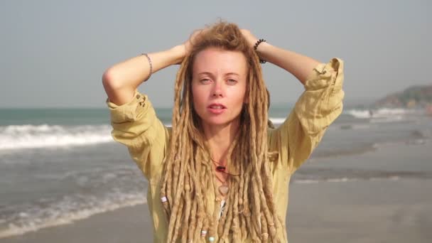 Portret van een jonge vrouw met dreadlocks haar op een achtergrond van de zee — Stockvideo