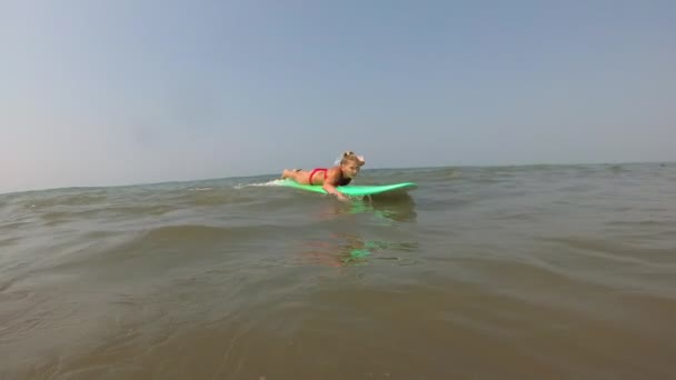 En ung kvinna lär sig surfa och ramlar av en surfbräda. Flicksurfare i havet — Stockvideo