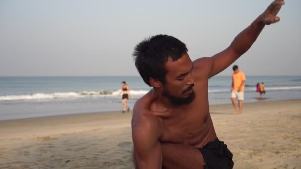 En man utövar yoga. Manlig yogi. Asiatisk man utövar yoga på stranden — Stockvideo