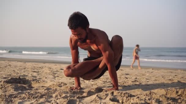 Um homem na praia faz ioga. masculino yogi práticas ioga asanas — Vídeo de Stock