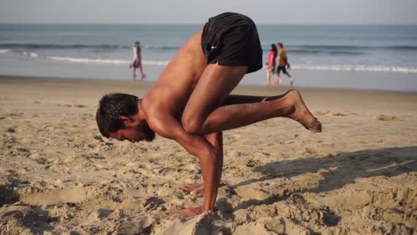 En man utövar yoga. En man utför en asana handstand i yoga — Stockvideo