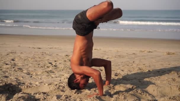 Um homem pratica ioga. O Yogi está de cabeça erguida. Asanas de ioga — Vídeo de Stock