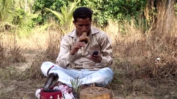 Um encantador de serpentes a falar ao telefone na rua. Índia tradicional — Vídeo de Stock