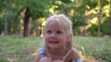 Parktaki güzel sarışın bir kızın portresi. Çocuk gülümsüyor, yakından.