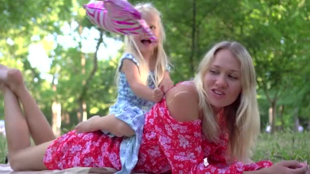 Retrato de una mujer y un niño en un parque de verano. Mamá y su hija están jugando en el parque — Vídeos de Stock