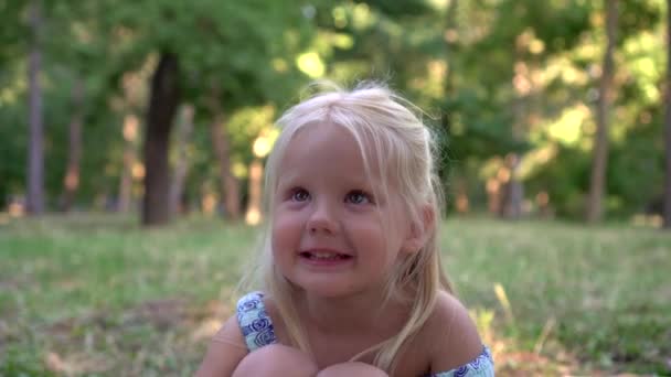 Portrait d'une jolie blonde mignonne dans le parc. L'enfant sourit, gros plan