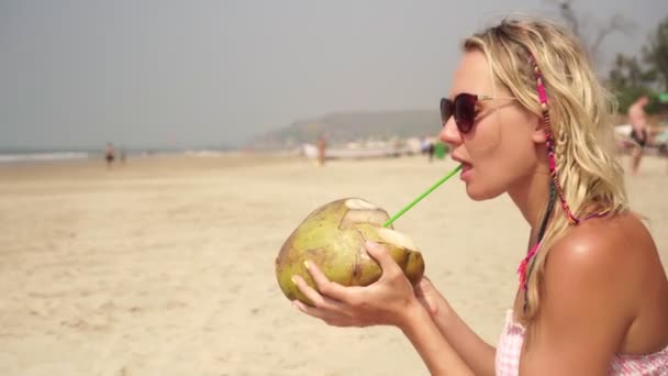 Mladá krásná žena pije kokos na tropické mořské pláži — Stock video