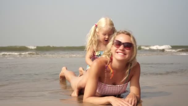 Familia feliz, mamá y el bebé tomar el sol en la playa del mar — Vídeo de stock