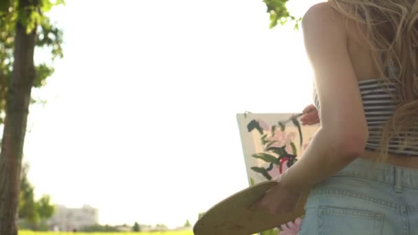 Seniman wanita kreatif muda melukis sebuah gambar di alam saat matahari terbenam — Stok Video