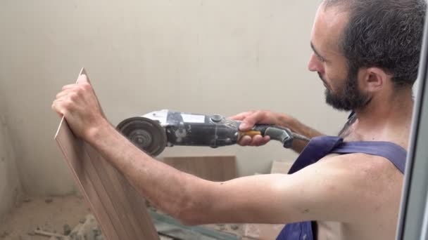 Worker sawing tiles with an angle grinder. A man makes repairs and saws tiles — Stock Video