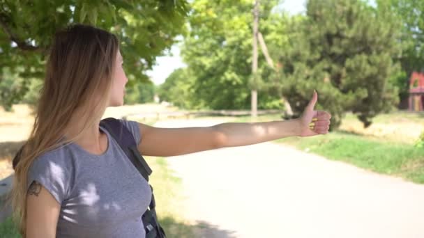 Eine Frau trampt auf einer Landstraße. Mädchen reist per Anhalter — Stockvideo