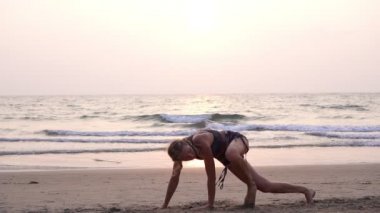 Kumsalda genç kadın antrenman ve dövüş sanatları yapıyor.