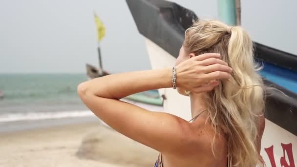 Młoda piękna blondynka na plaży patrzy na morze — Wideo stockowe