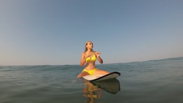 Fiatal szexi nő ül egy szörfdeszkán a tengerben. Szörfös lány a tengerben — Stock videók