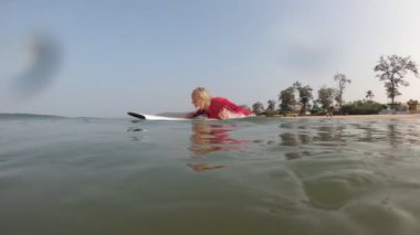Yetişkin bir yaşlı adam denizde sörf yapıyor. Yaşlılıkta aktif yaşam kavramı.