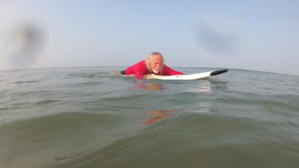 Ένας ενήλικος γέρος κάνει σερφ στη θάλασσα. Ενεργή ζωή στα γηρατειά. — Αρχείο Βίντεο