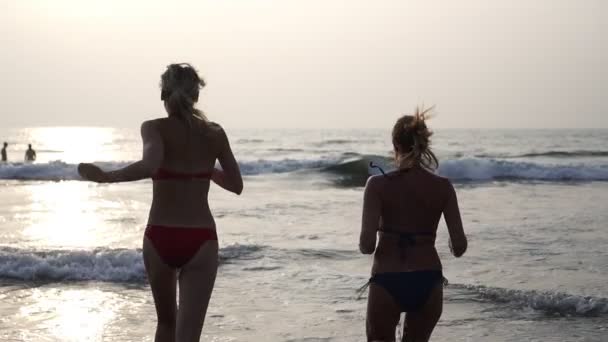 Jóvenes mujeres hermosas corren por la noche para nadar en el mar con salpicaduras — Vídeos de Stock