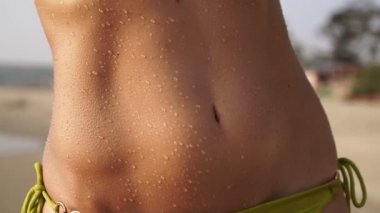 Sahildeki seksi kadın. Mayo giymiş güzel bir kızın göbeği ve vücudu.