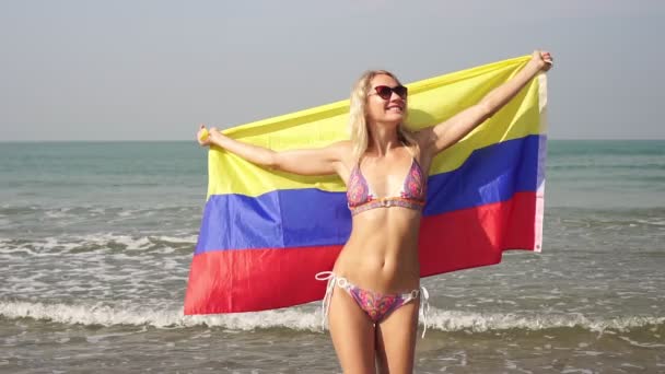 Beautiful woman with flag of Colombia on the background of the sea, slow motion — Stock Video