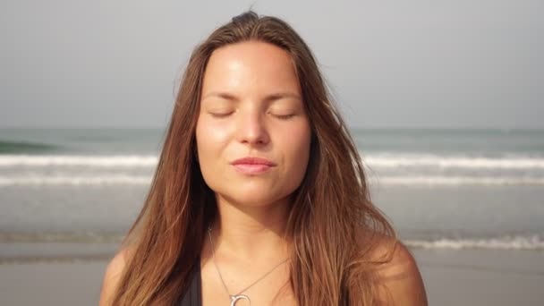 Retrato de uma jovem mulher contra o fundo do mar com olhos fechados — Vídeo de Stock