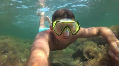 Maskeli bir adam denizin altında yüzer. Dalgıç denizde yüzer.