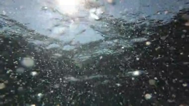 Denizde suyun altında hava kabarcıkları ve güneş ışınları. Deniz suyu arkaplanı