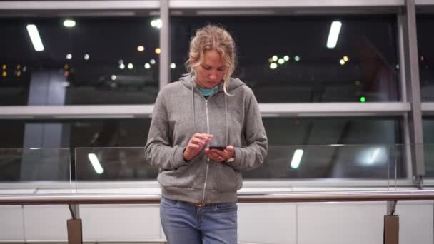 Giovane turista utilizza uno spartphone nel terminal dell'aeroporto o stazione ferroviaria — Video Stock