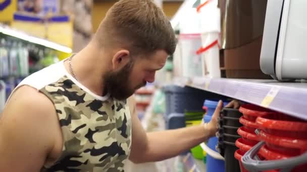 Un comprador masculino selecciona un producto en un supermercado o tienda de mejoras para el hogar — Vídeos de Stock