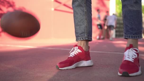 Un hipster en chaussures de sport sur fond de terrain de basket. — Video