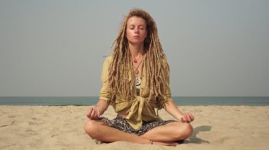 Rastalı hippi kız dışarıda yoga ve meditasyon yapıyor.