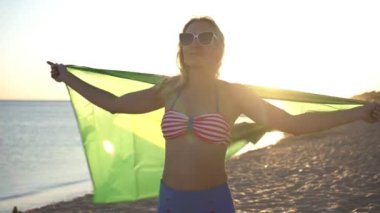 Brezilya bayrağıyla deniz sahilinde genç bir kadın. Brezilya bayrağıyla gün batımına karşı mayolu bir kız..