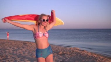 Deniz sahilinde İspanyol bayrağı taşıyan güzel bir kadın. İspanya bayrağıyla mayo giymiş bir kız.