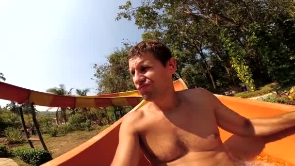 Triste hombre aburrido se desliza lentamente por el tobogán de agua en el parque acuático — Vídeos de Stock