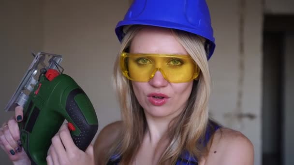 Kasklı ve elektrikli testereli seksi bir kadın inşaatçının portresi. — Stok video