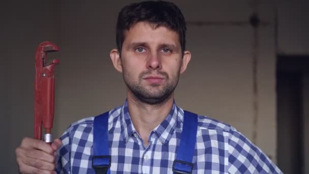 Portrait of a young attractive male plumber with a plumbing wrench — Stock Video