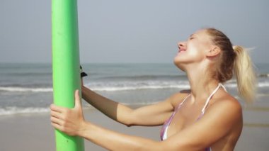 Güneşli deniz sahilinde sörf tahtası olan güzel bir kadının portresi.