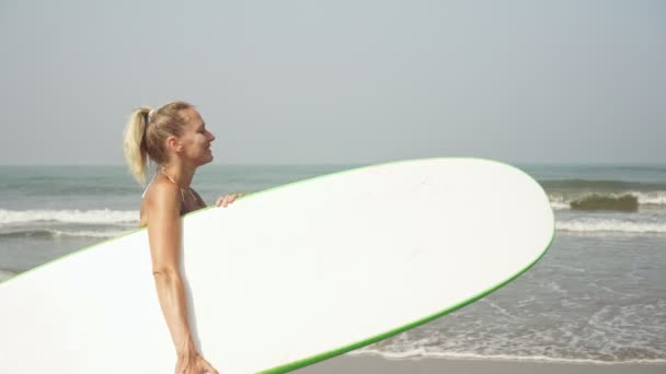Jonge aantrekkelijke vrouw op het strand draagt een surfplank. Surfervrouw — Stockvideo