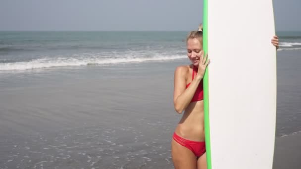 Młoda seksowna kobieta w czerwonym bikini z deską surfingową na plaży morskiej — Wideo stockowe