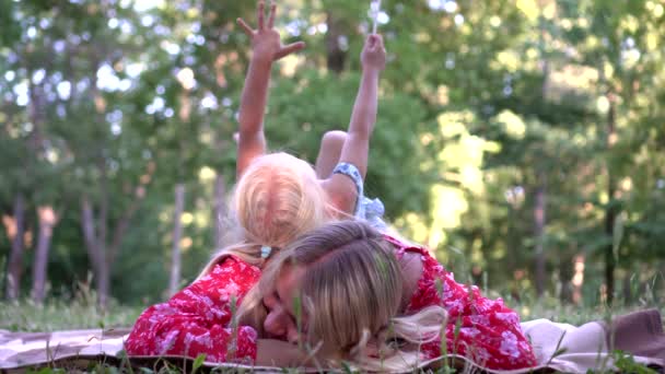 Famiglia felice, mamma e figlioletta stanno riposando su una coperta nel parco all'aperto — Video Stock