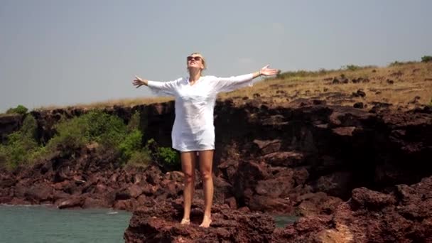 Une femme se tient sur un rocher et étend ses bras sur les côtés jouissant de la liberté — Video