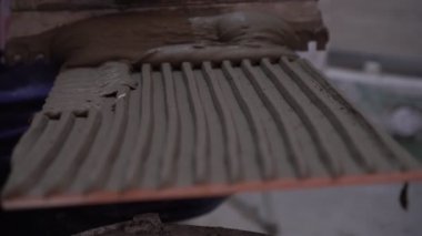 Bir işçi onarımlar yapar ve fayanslara çimento yapıştırıcısı sürer.