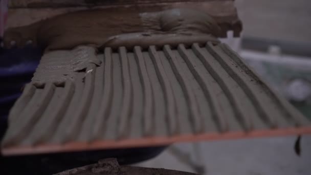 Een arbeider repareert en brengt cementlijm aan op de tegels — Stockvideo