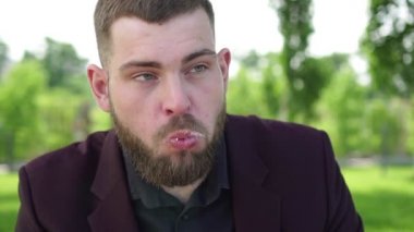 Aç iş adamı ya da yönetici parkta sandviç yiyor.