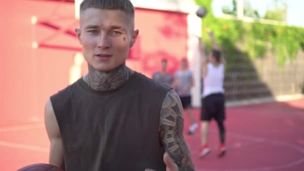 Porträtt av en ung modern man med tatueringar på en basketplan. Modern ungdomsbild — Stockvideo