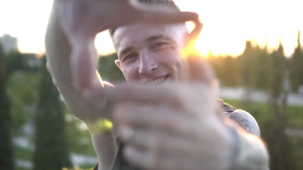 Portret van een jonge aantrekkelijke man tegen de achtergrond van de zonsondergang. Mannelijke cameraman of regisseur. Hedendaagse jeugd en straatmode — Stockvideo