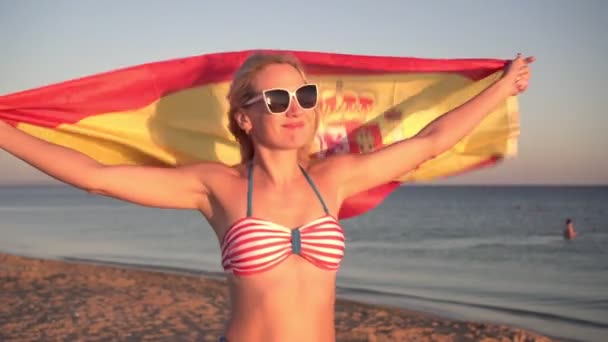 Jovem atraente com a bandeira da Espanha na praia de areia do mar. Espanhol com a bandeira nacional à beira-mar — Vídeo de Stock