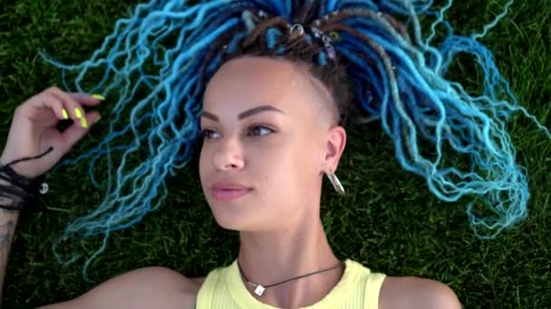 머리칼을 가진 매력적 인 젊은 여자가 푸른 잔디 위에 누워 있다 — 비디오