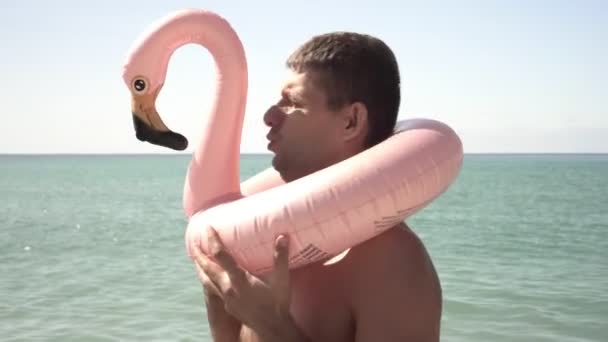 Портрет забавного веселого человека с надувным плавательным кольцом на фоне моря — стоковое видео