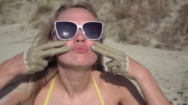 Genç neşeli kadın cildine kozmetik kil ya da çamur sürer.